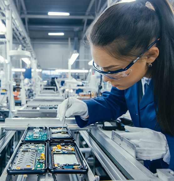 Woman technician placing circuit board in factory assembly line.