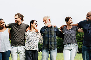 A diverse group of smiling people standing arm in arm.