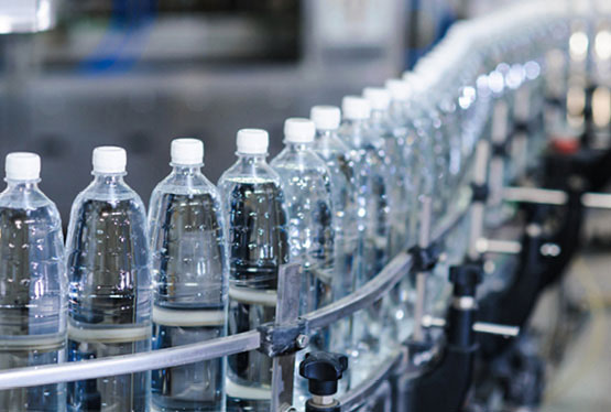 Water bottles in a track being processed at a factory.