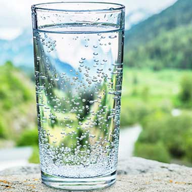 A clear glass of water contains small traces of sodium, typically introduced in water softening. Excess sodium causes negative health effects.