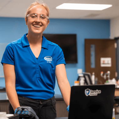 Smiling Hach Service Representative in blue Hach button down shirt and safety goggles at laboratory bench performing instrument service.