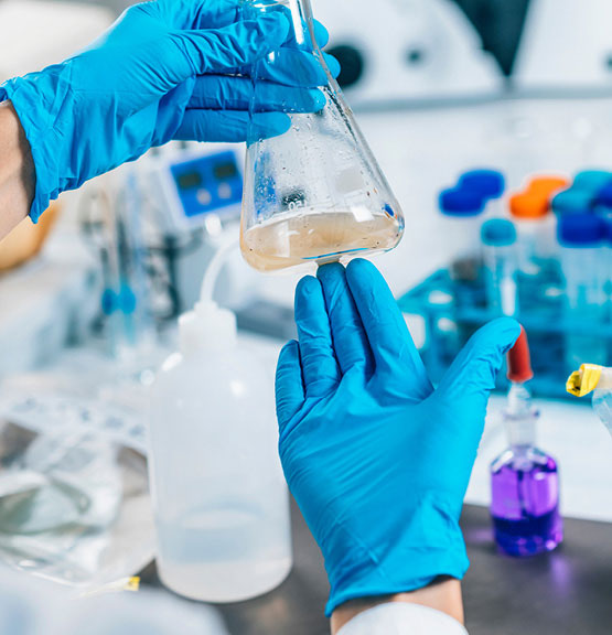 A technician wearing protective gloves examines the water turbidity within a laboratory.